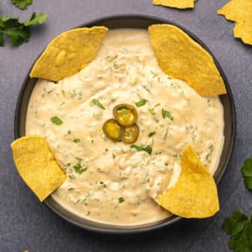 Cashew queso in a black bowl with tortilla chips.