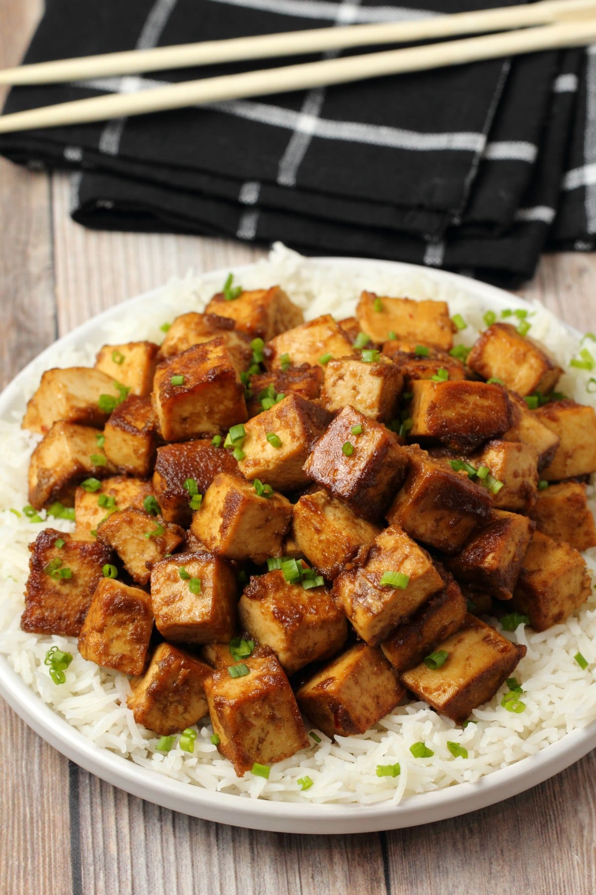 Marinated tofu topped with chopped chives on a bed of rice. 