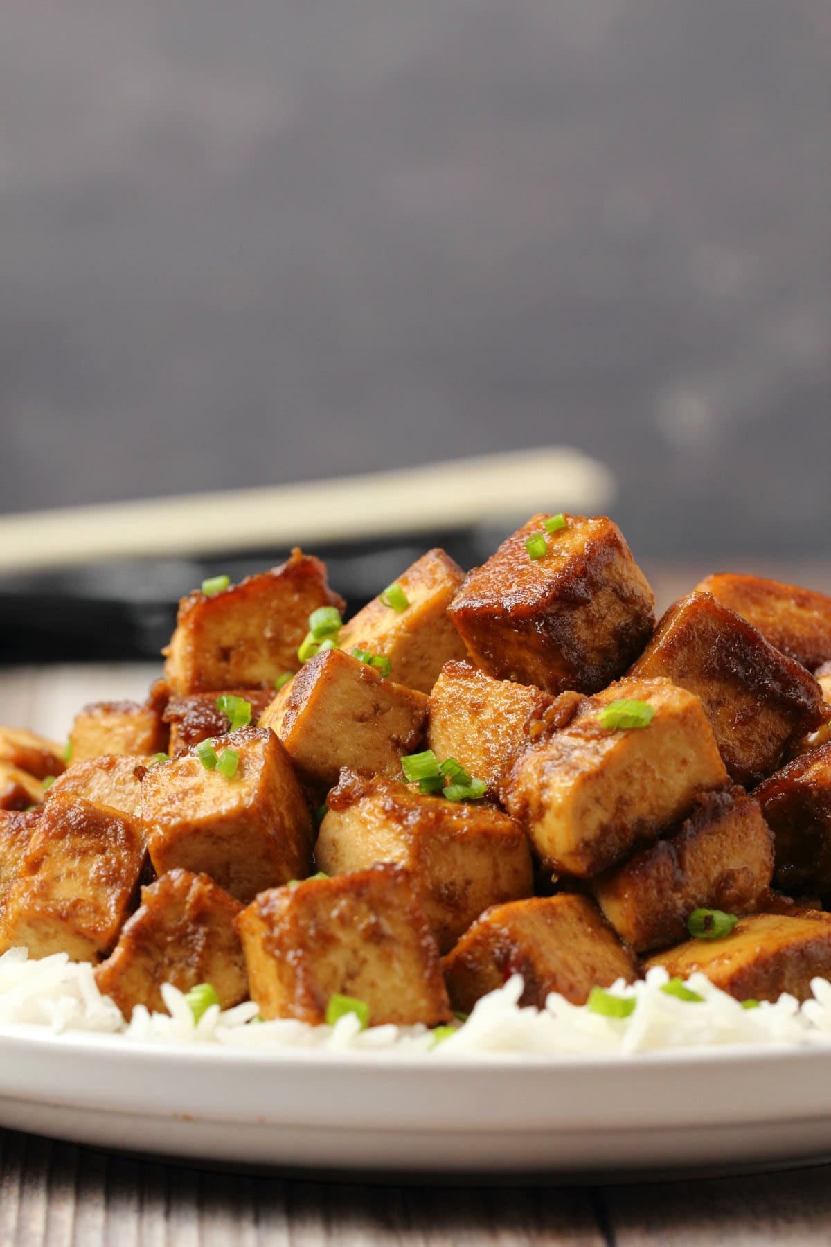 Marinated tofu topped with chopped chives and on a bed of rice. 
