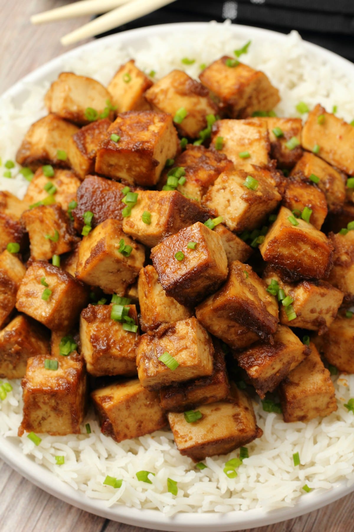 Marinated tofu topped with chopped chives on a bed of rice. 