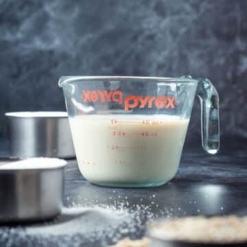 Flour, soy milk, sugar and oats in measuring cups.
