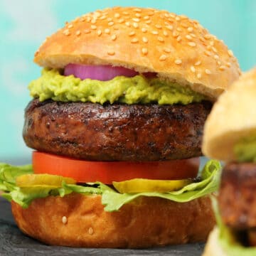 Vegan black bean burger topped with guacamole and red onion in a burger bun.