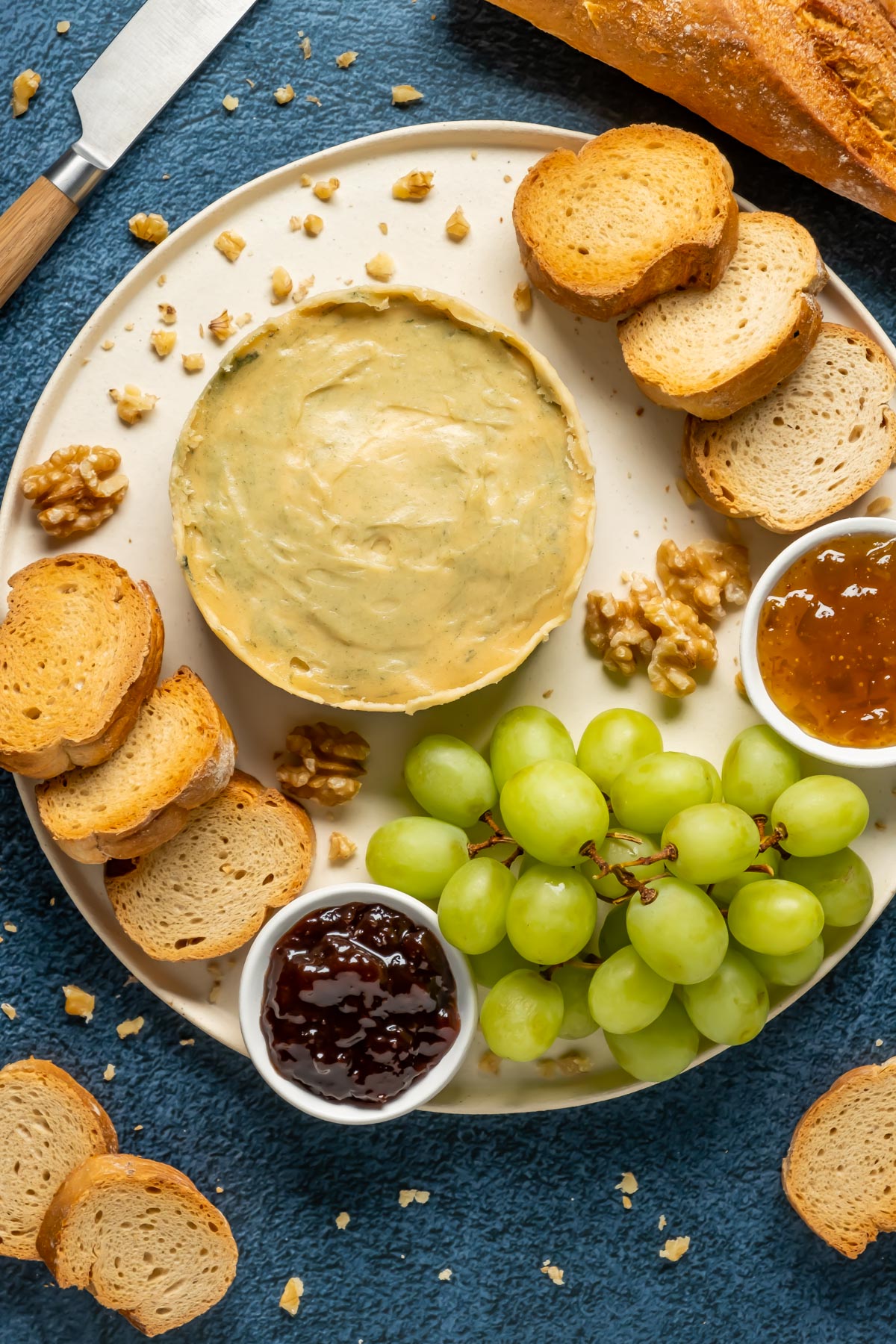 Vegan blue cheese on a white plate with toasted bread, grapes and jams. 