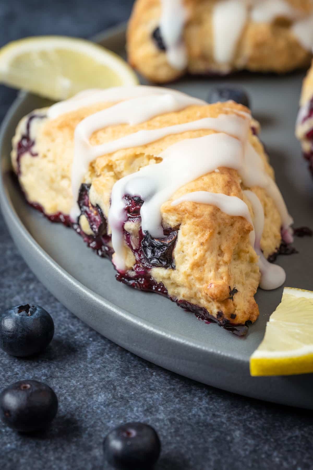 Glazed blueberry scones on a gray plate.