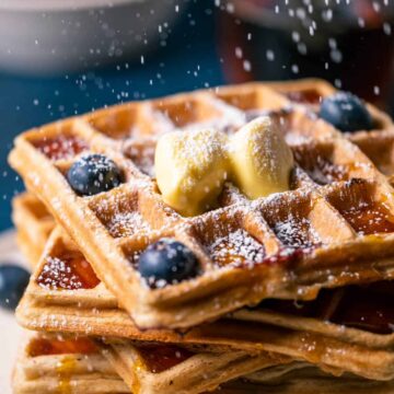 Stack of blueberry waffles on a white plate.