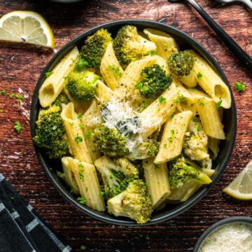 Vegan broccoli pasta with vegan parmesan in a black bowl.