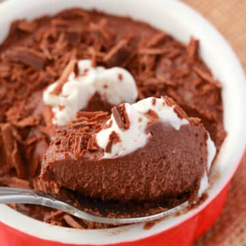 Vegan chocolate mousse in a ramekin with a spoon.