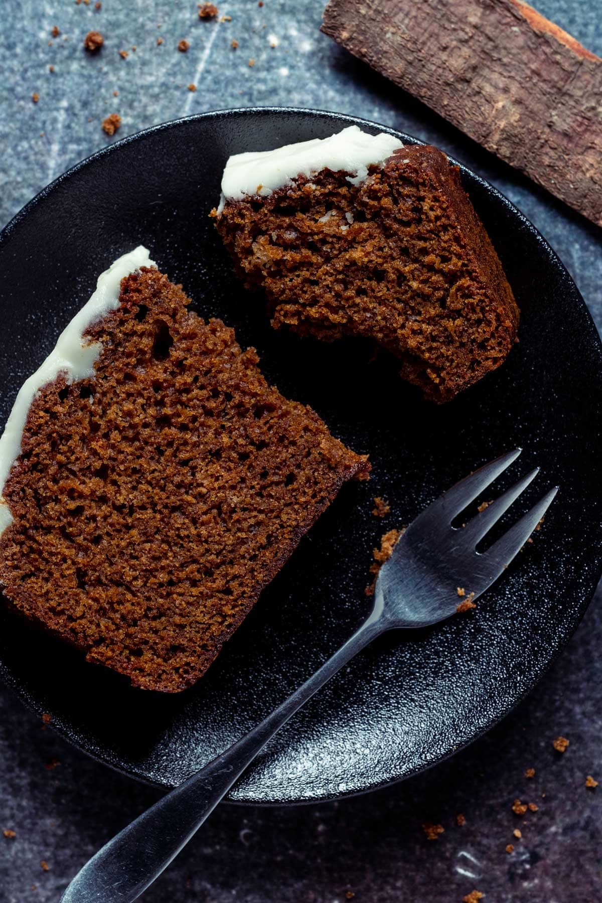 Slice of gingerbread loaf on a black plate with a cake fork.