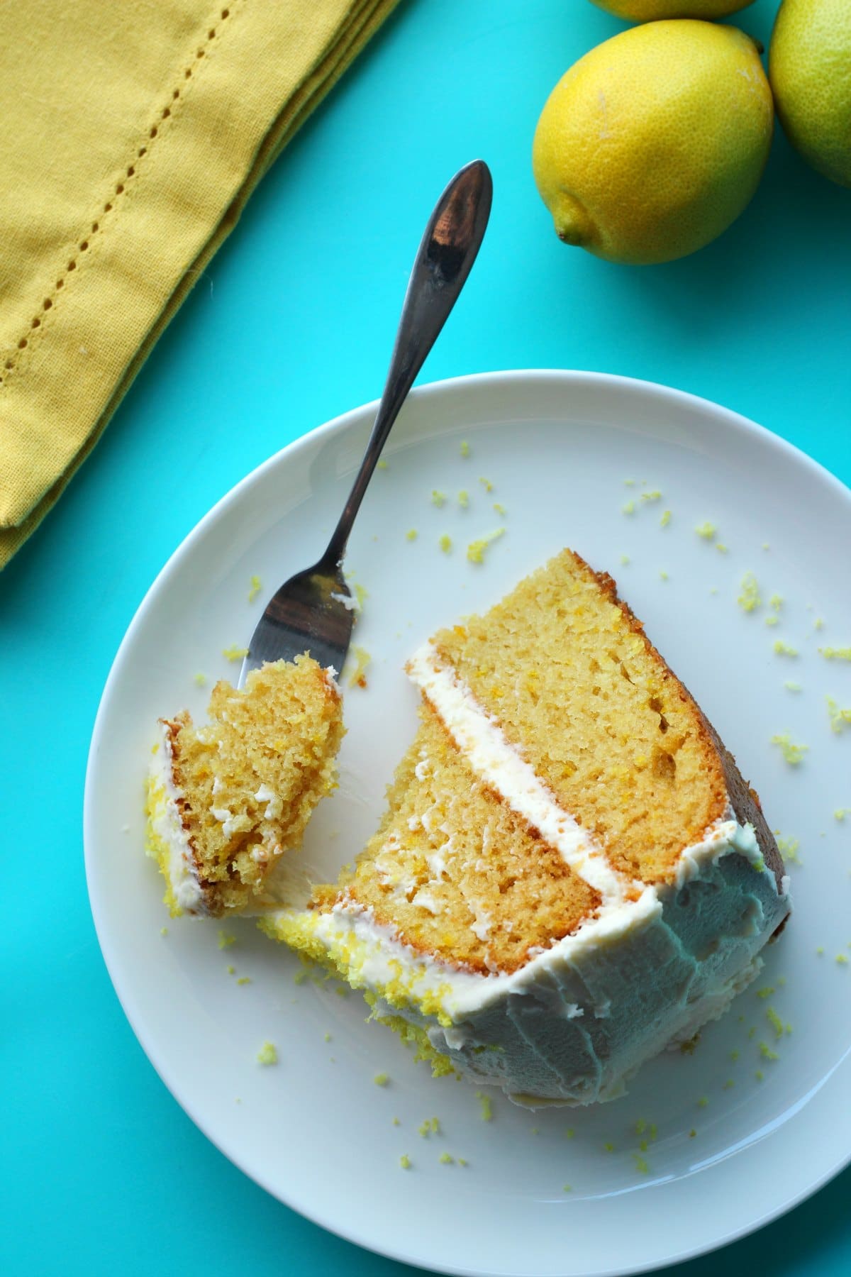 A slice of lemon cake on a white plate with a cake fork. 