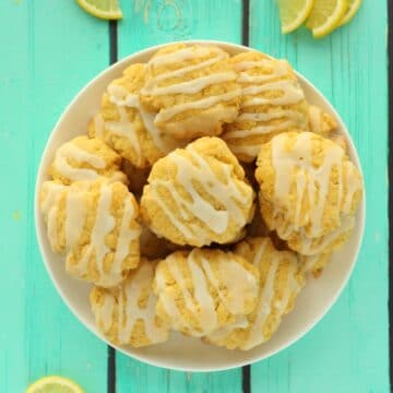Vegan lemon cookies stacked up on a white plate.