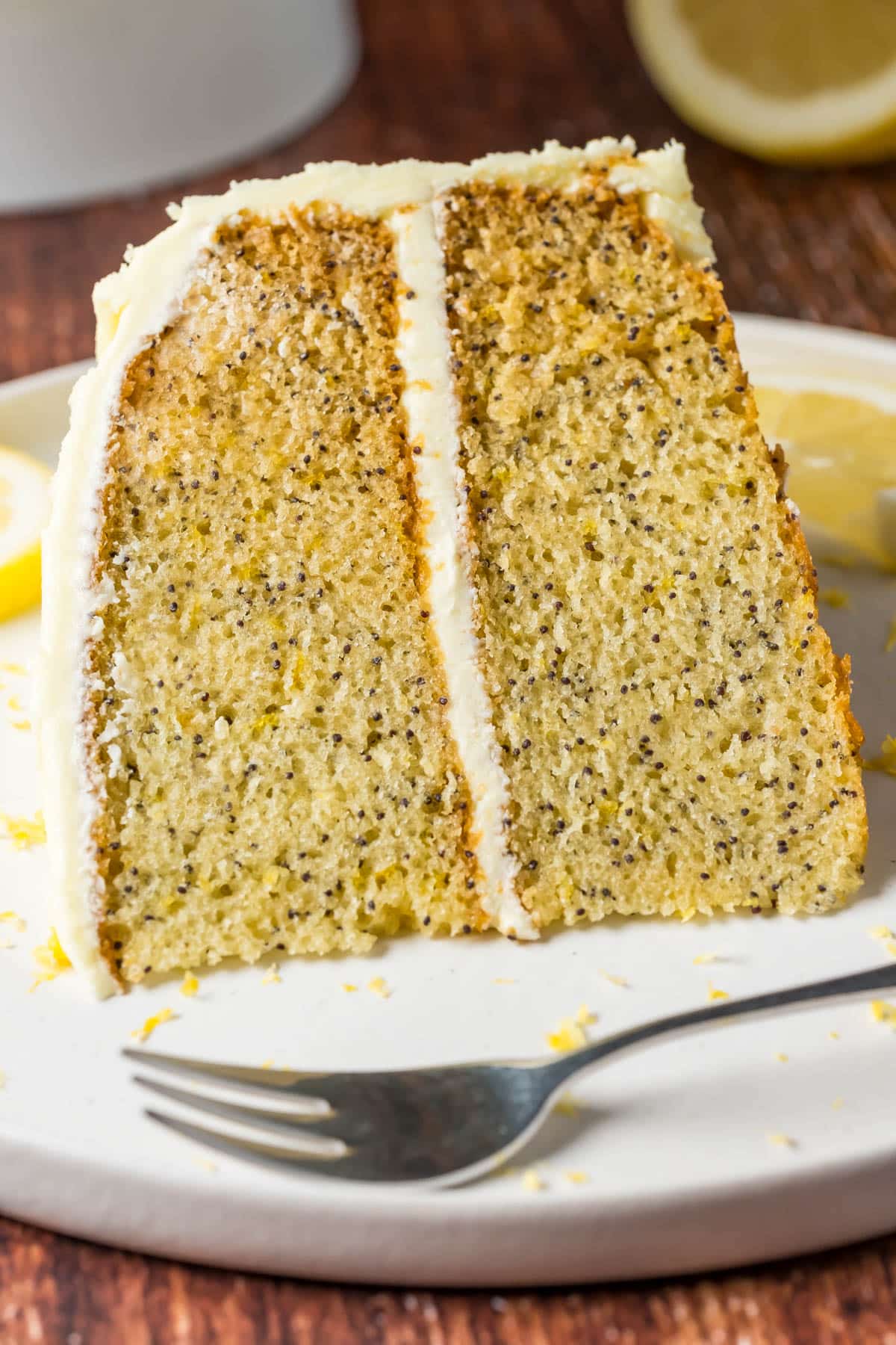 Slice of vegan lemon poppy seed cake on a white plate with a cake fork.