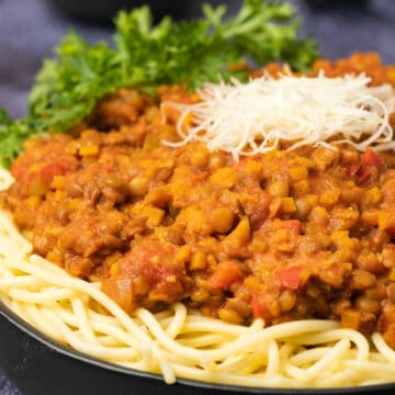Lentil bolognese with spaghetti in a black bowl.
