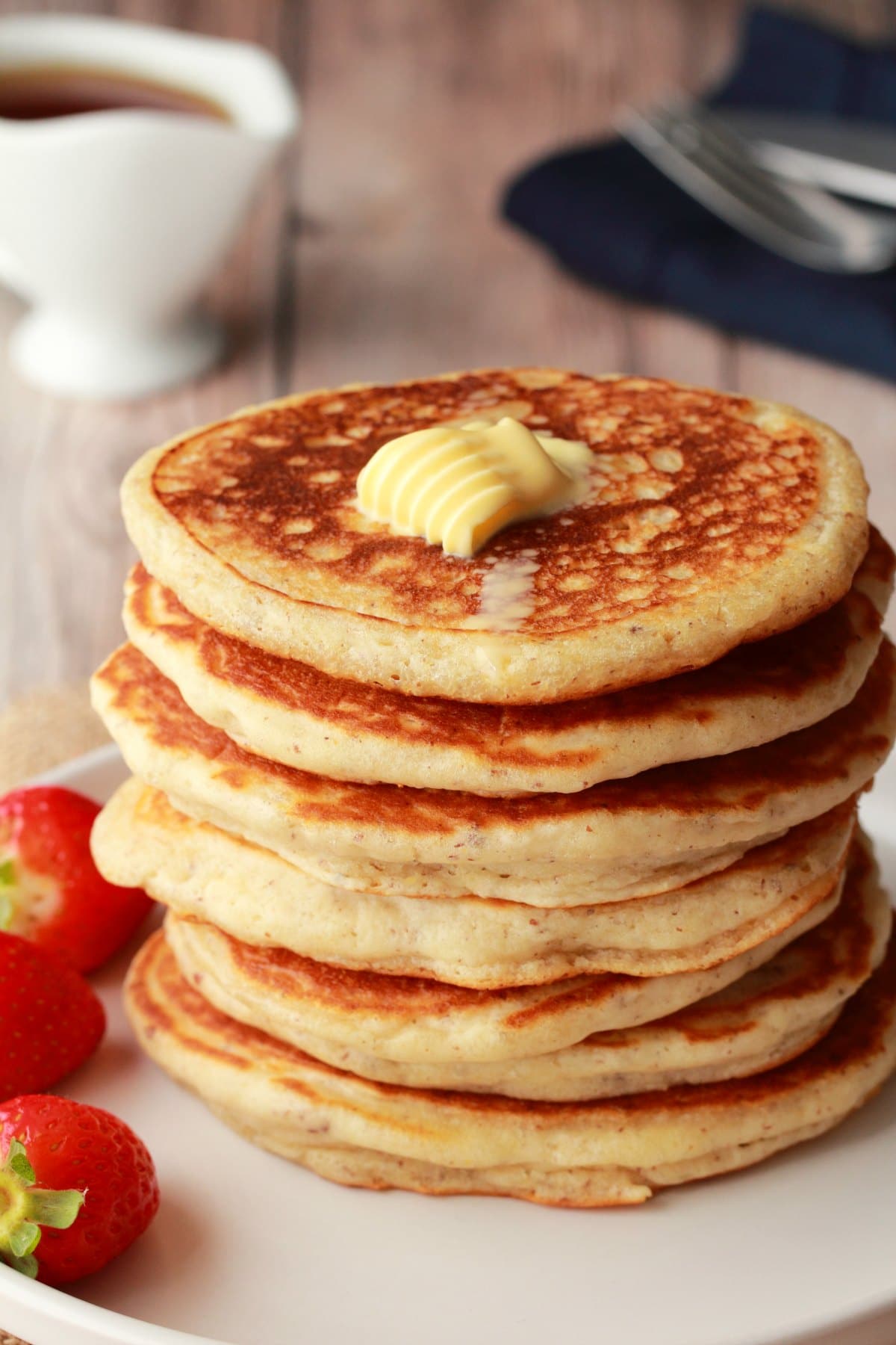 A stack of vegan pancakes topped with vegan butter on a white plate. 