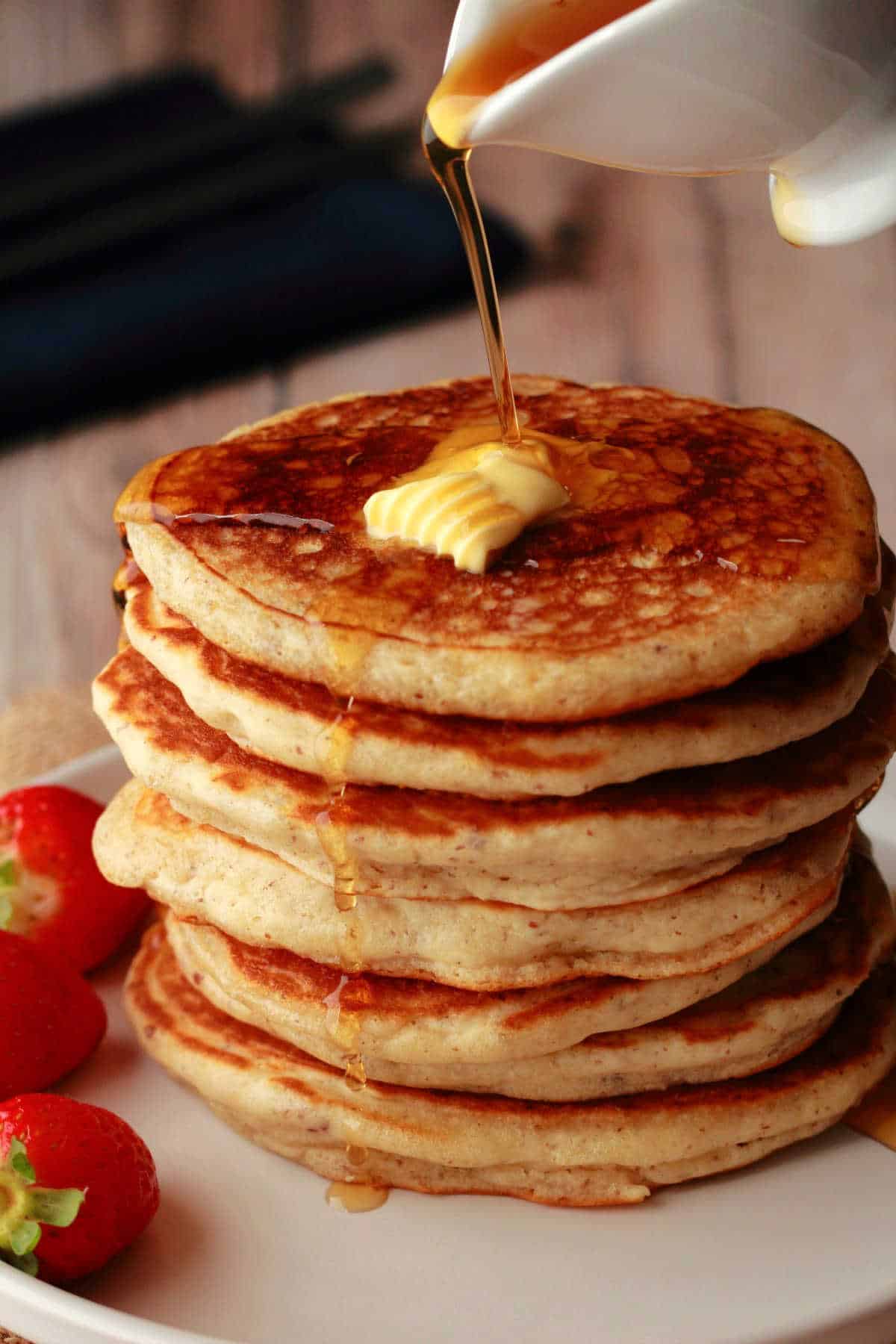 Vegan pancakes in a stack with syrup pouring over them.