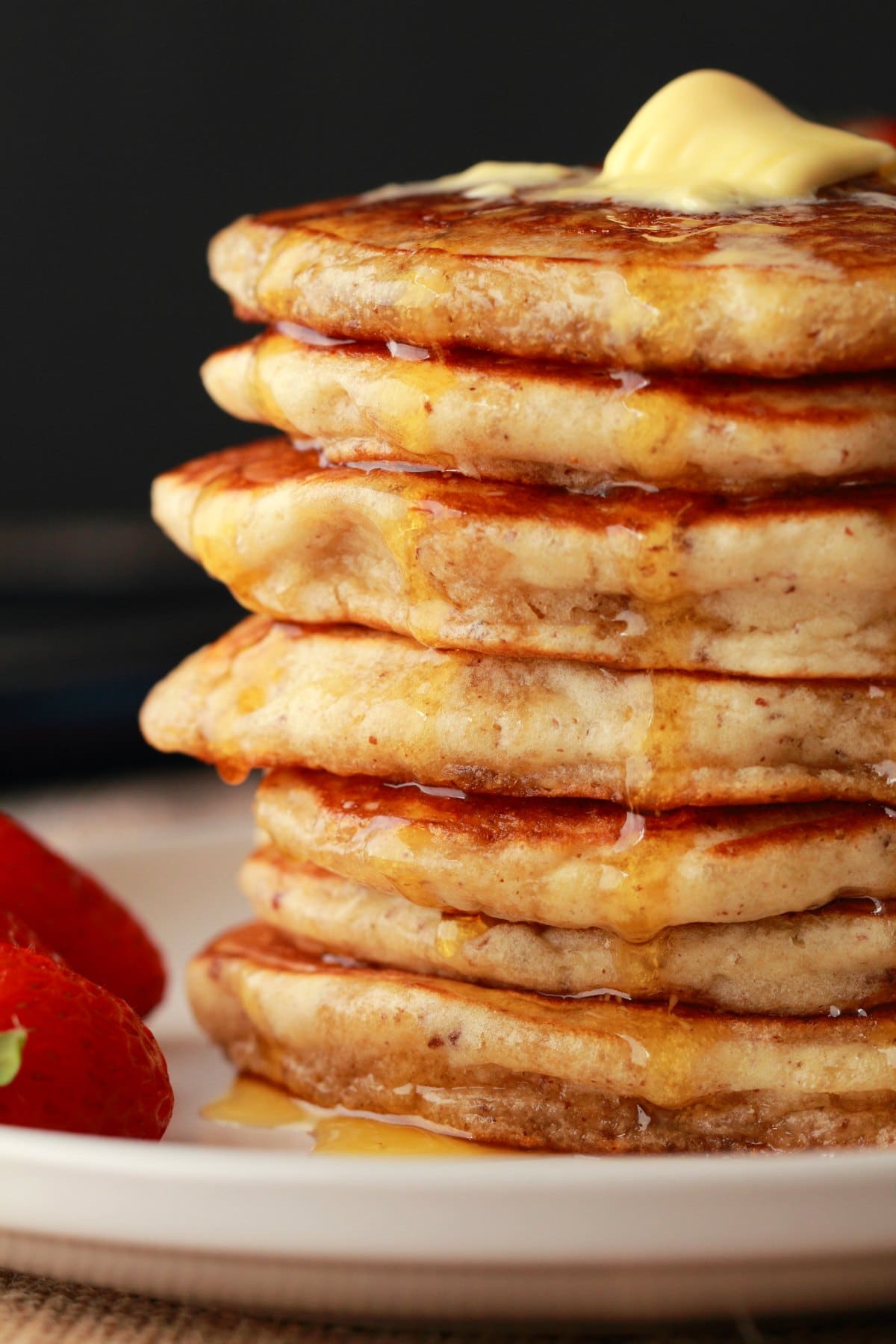 Stack of vegan pancakes with syrup drizzling down the sides. 