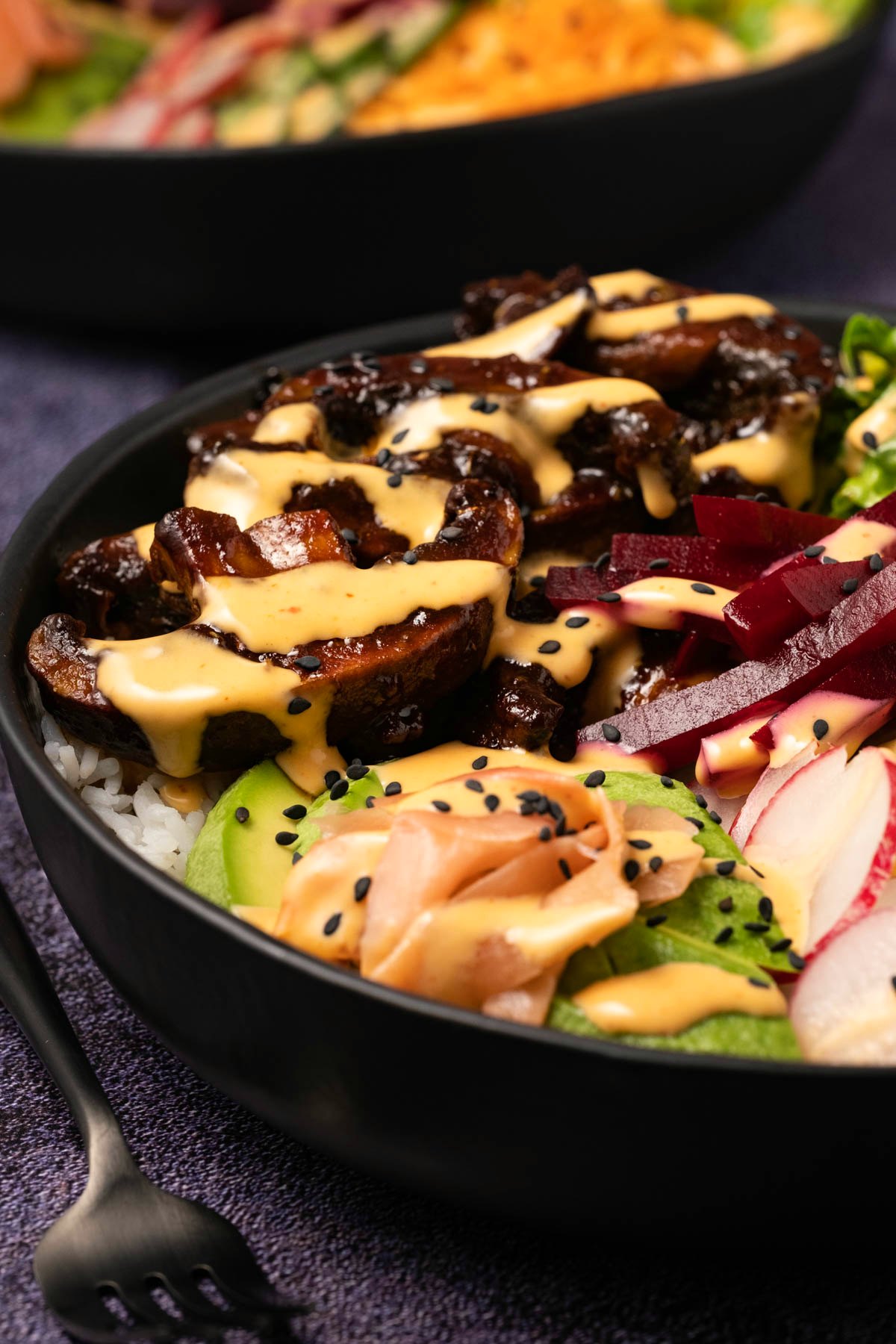 Black bowl with veggies, rice and salad. 