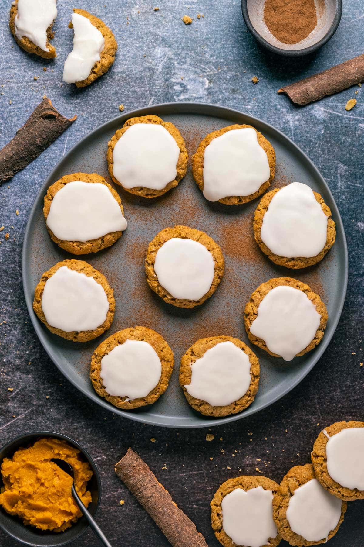 Frosted pumpkin oatmeal cookies on a gray plate.