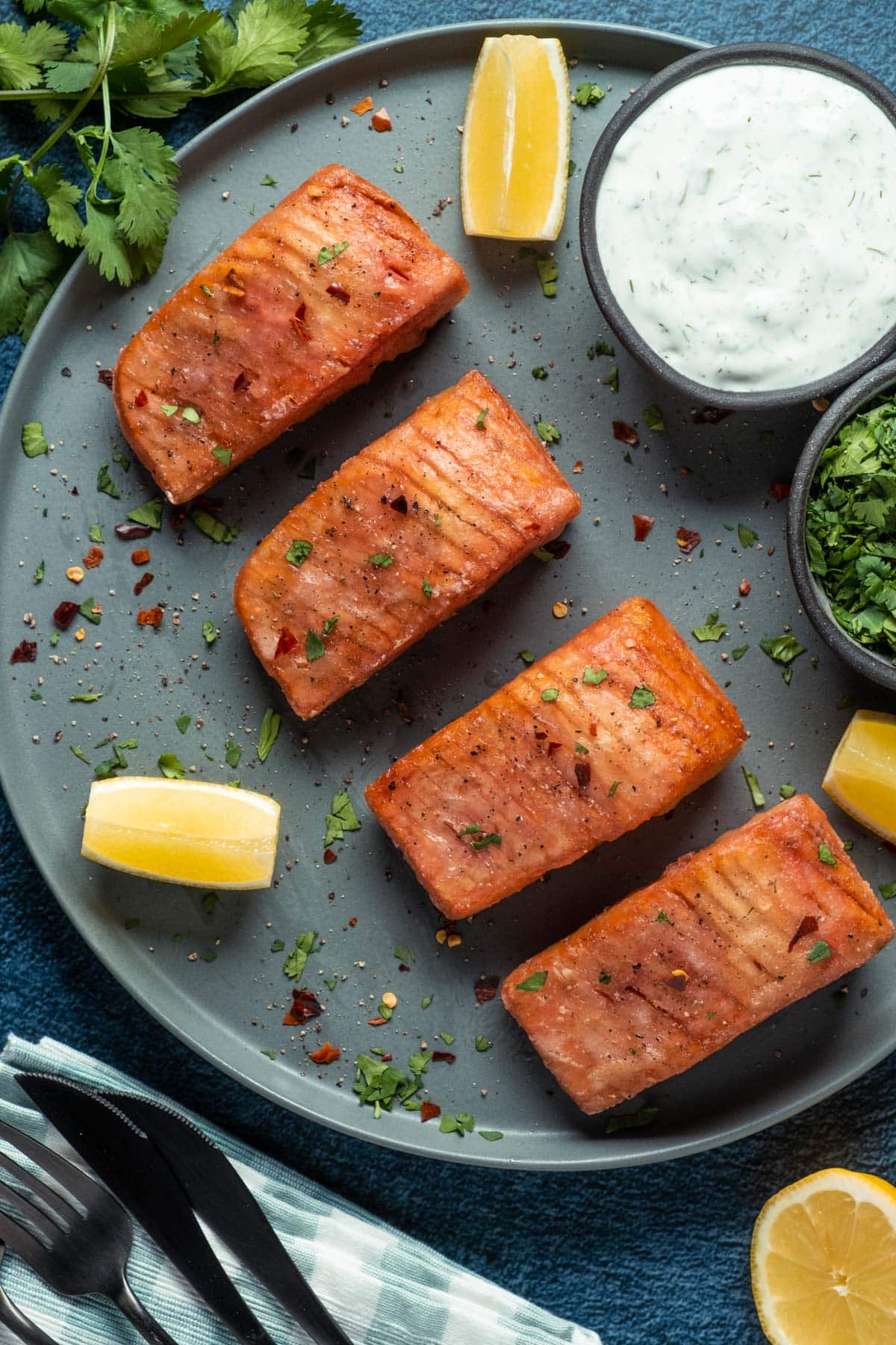 Vegan salmon on a plate with lemon wedges, tartar sauce and chopped cilantro.
