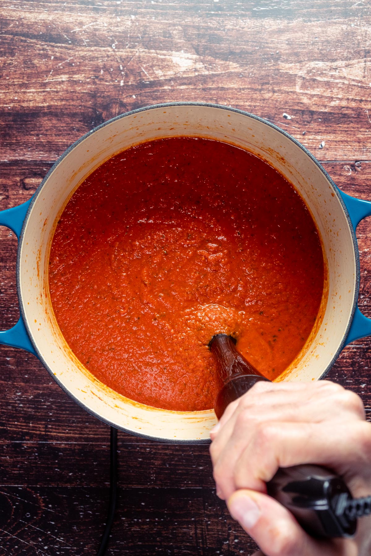 Blending spaghetti sauce in the pot with an immersion blender.