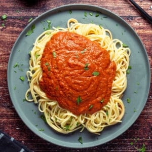 Vegan spaghetti sauce over spaghetti on a gray plate.