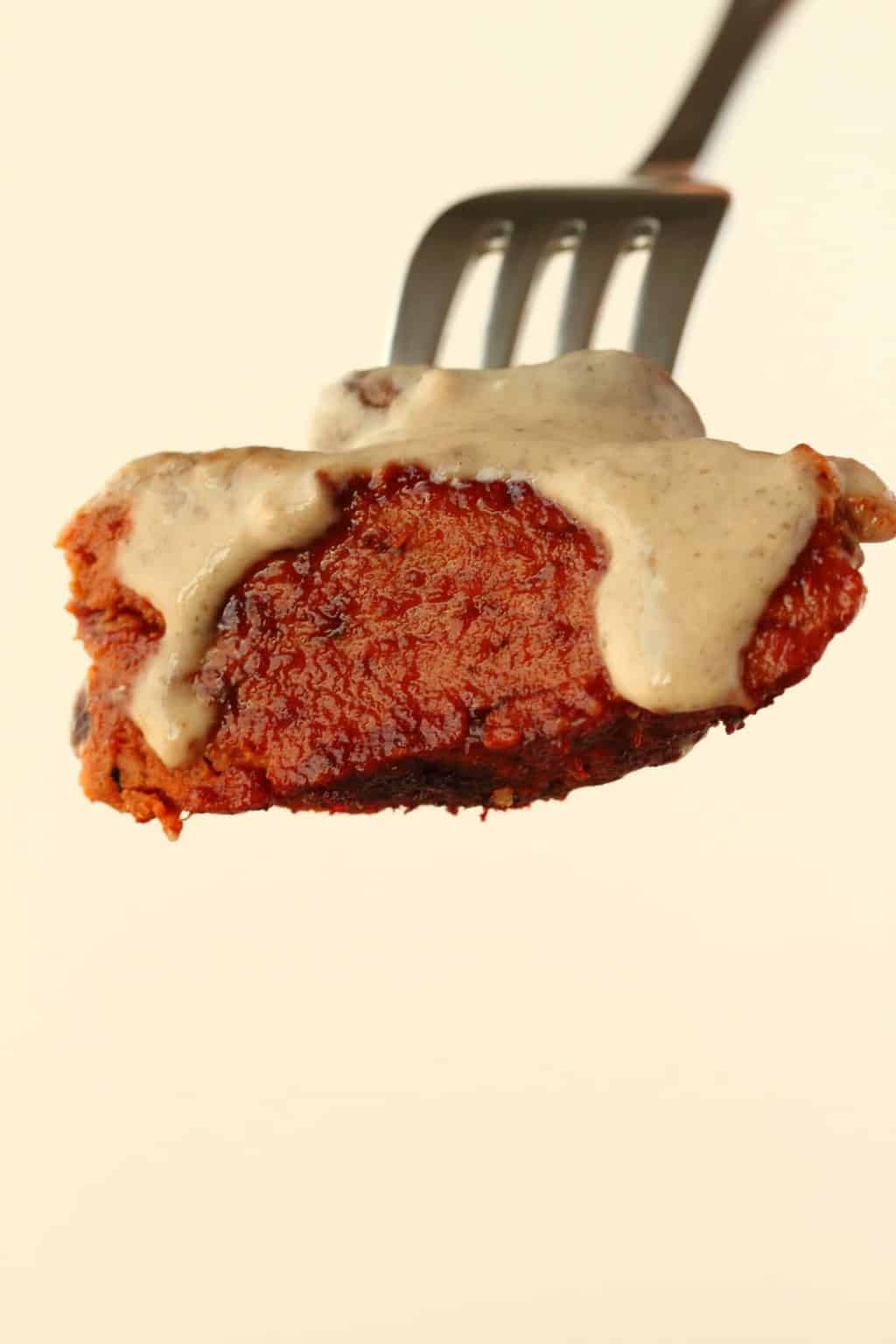 A forkful of vegan steak covered in mushroom sauce. 