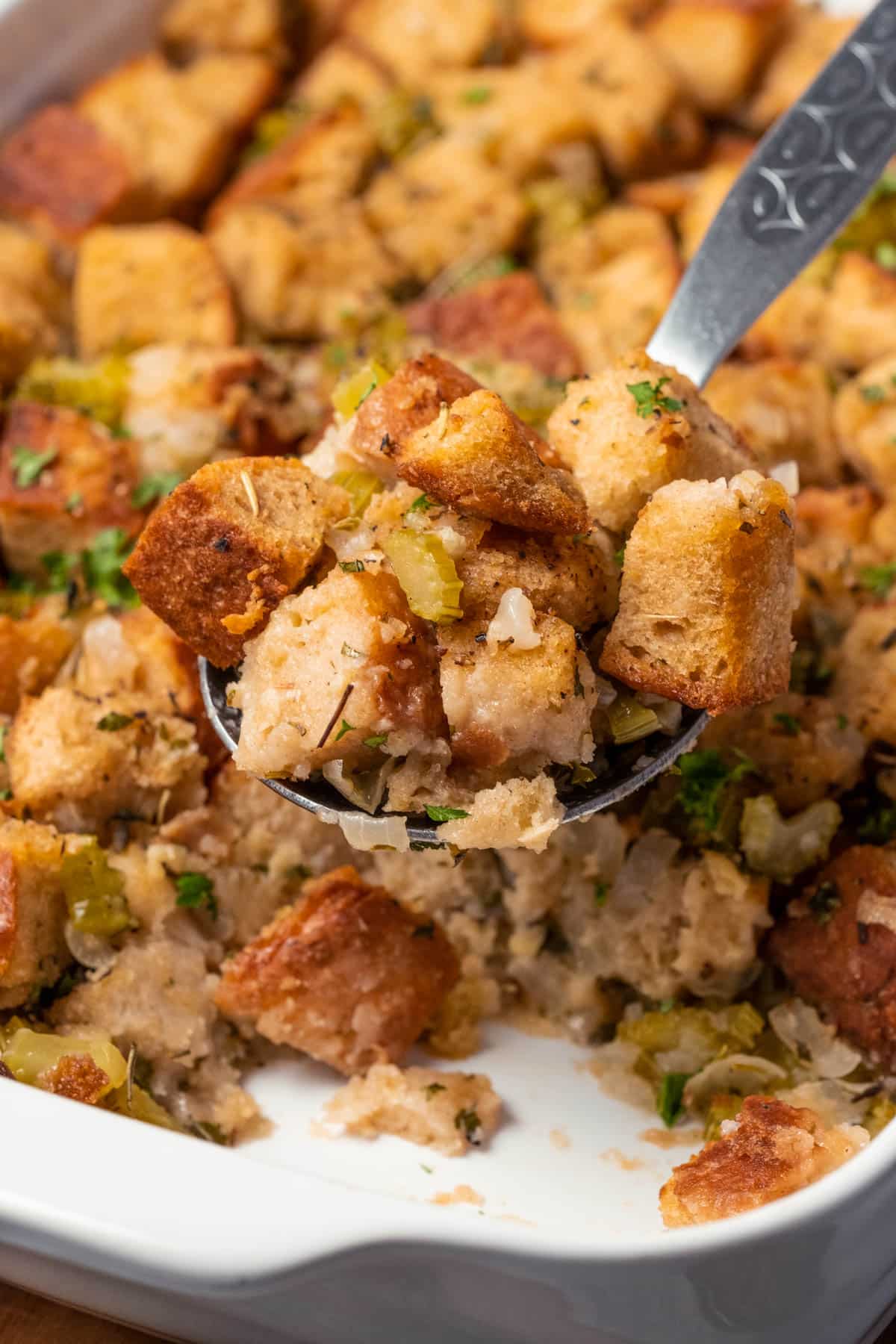 Vegan stuffing in a white dish with a serving spoon.