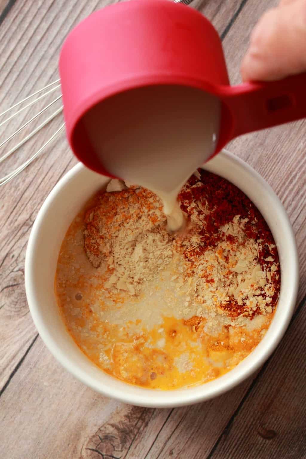Pouring soy milk into a bowl with spices. 