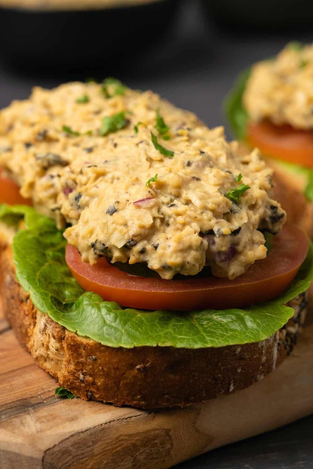 Vegan tuna spread on top of a slice of bread with tomato and lettuce. 
