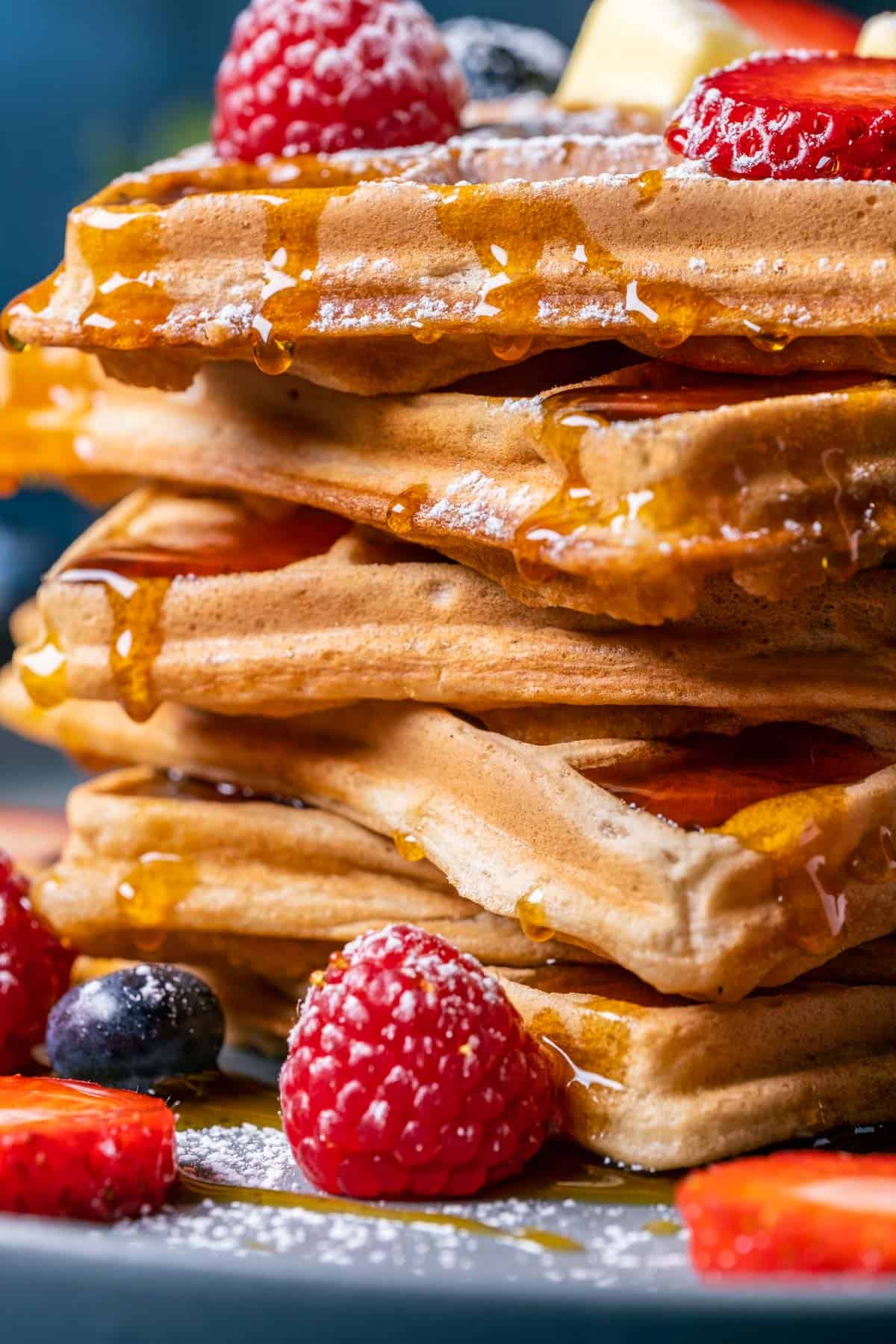 Stack of waffles with drizzled syrup, fresh berries and vegan butter.